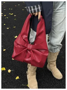 Sac cabas rouge avec un grand nœud papillon dans un cadre de parc extérieur élégant