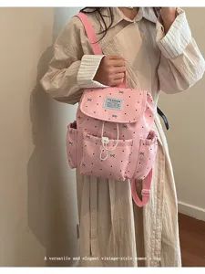 Close-up of a pink polka dot backpack featuring bow detailing and a drawstring closure