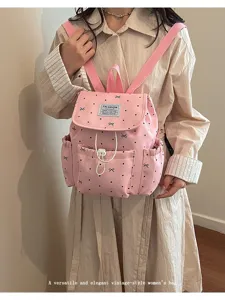Detail of a pink polka dot backpack with drawstring and bow accents on a model