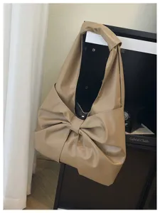 Détail du design élégant avec un grand nœud sur un sac fourre-tout beige en similicuir