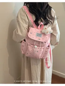 Pink polka dot backpack with bow pattern and plush charm shown in a lifestyle setting