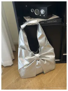 Détail du sac hobo métallisé argenté avec un grand nœud et une finition brillante
