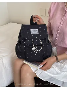 Black polka dot drawstring backpack with bow prints held by model in casual lifestyle setting