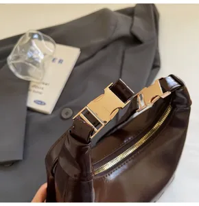 Close-up of golden buckles and premium oil wax leather texture on a brown handbag