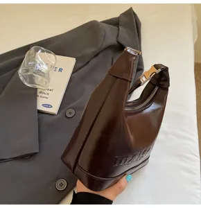 Detailed side view of dark brown oil wax leather handbag with maison embossed lettering