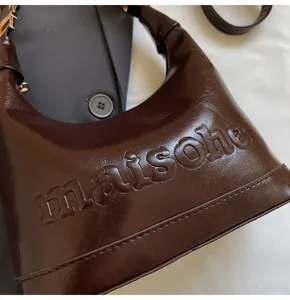 Close-up of a dark brown oil-wax leather handbag featuring an embossed maisohe logo