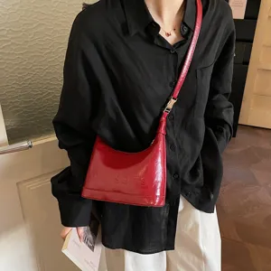 Close-up of a vintage red oil-wax leather crossbody bag on a model wearing black shirt