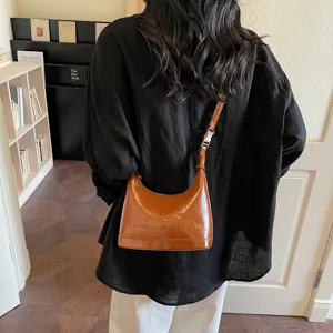 Rear view of model carrying a brown oil-wax leather crescent crossbody bag indoors.