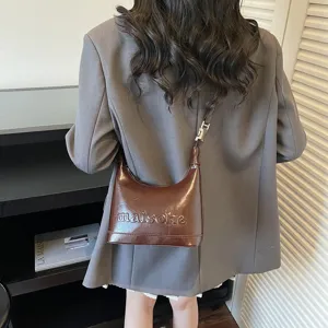 Stylish back view of a brown oil wax leather hobo bag on a model wearing a grey blazer
