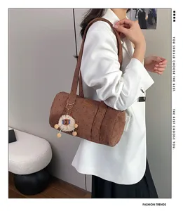 Vue détaillée d'un sac bandoulière en velours côtelé marron avec un blazer blanc