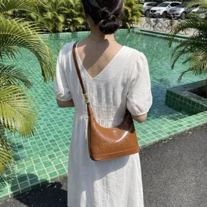 Elegant brown oil-wax leather shoulder bag for women with minimalist embossed detail.