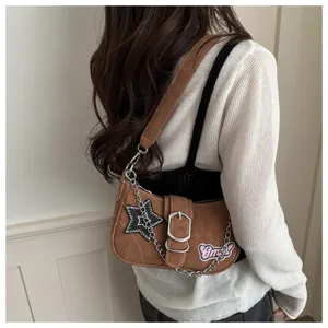 Detailed view of a Y2K style brown underarm bag featuring a star patch and chain strap detail
