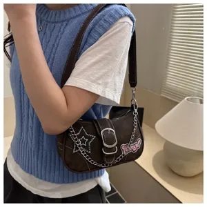 Detailed view of brown Y2K baguette shoulder bag with star and chain on model