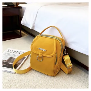 Piccola borsa a tracolla in nylon giallo con doppia cerniera in un ambiente camera