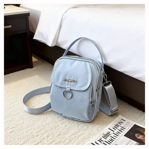 Primo piano di una piccola borsa a tracolla in nylon azzurro su un morbido tappeto crema