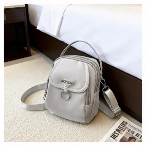 Primo piano di una mini borsa a tracolla in nylon grigio chiaro in un ambiente accogliente