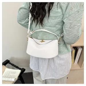 Gros plan d'un sac à main blanc minimaliste avec fermoir doré dans un décor de vie