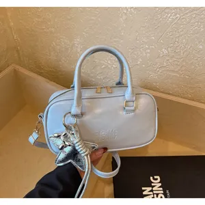 Close-up of a light blue Boston handbag with a silver star charm and embossed text.