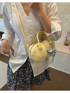 Stylish yellow Boston handbag with a silver star charm, shown worn crossbody.