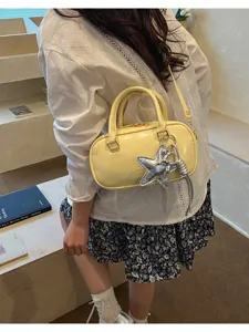 Lifestyle detail showing light yellow glossy Boston bag with silver star pendant