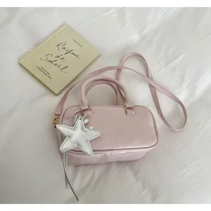 Detail view of pink Boston handbag with silver star charm and embossed logo detail