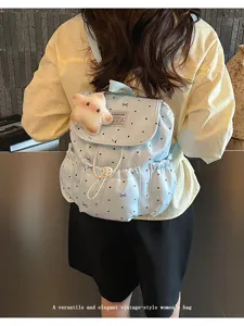 Back view of model wearing a light blue polka dot drawstring backpack with bow patterns