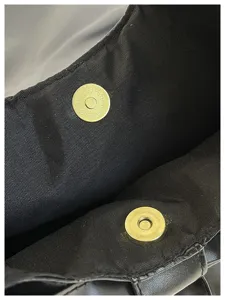 Gros plan sur le fermoir magnétique doré sur la doublure noire d'un grand sac cabas