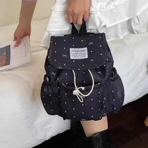 Small black backpack with white polka dots and bows featuring drawstring closure and top flap