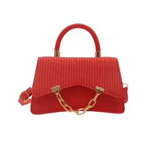 Fashionable red top handle handbag featuring woven flap and gold chain accent for women