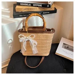 Detail einer handgefertigten Strohtasche mit Bambusgriff und eleganter Perlenschleife