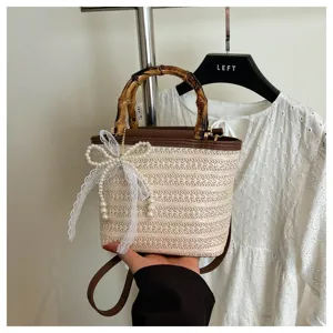 Nahaufnahme einer gewebten Stroh-Eimertasche mit Bambusgriff und eleganter Perlschleife