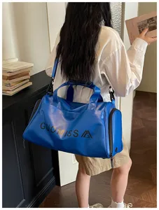 Detail view of blue sports duffel bag with handle and shoulder strap for fitness and travel.