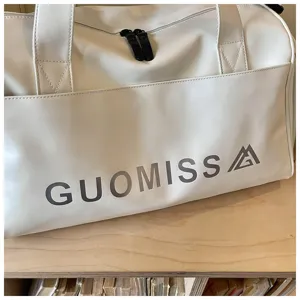 White leather gym duffel bag close up, featuring double zippers and front pocket design.