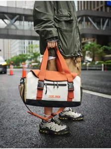 Detailansicht der modischen Color-Block-Reisetasche mit robusten Griffen und stabilen Schnallen.