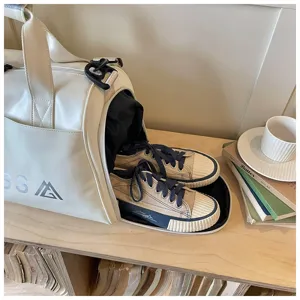 White fitness duffel bag with separate shoe compartment and casual canvas shoes for travel.