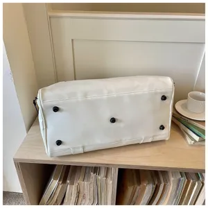 Detailed bottom view of the white travel duffel bag showcasing protective metal feet on a shelf.