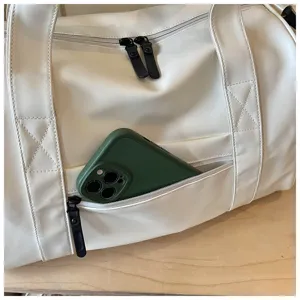 Detail view of white sports duffel bag front zipper pocket holding a green smartphone.