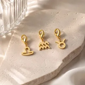 Primer plano de colgantes del zodiaco de acero inoxidable dorado con cierres de langosta.