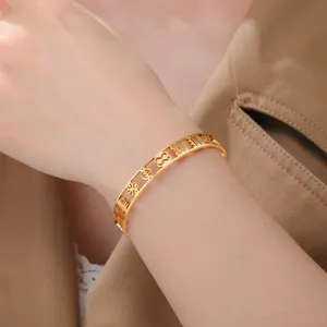 Detailed close-up of 18k gold plated cuff bracelet featuring intricate African Adinkra symbols