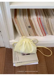 Minimalist yellow and white gingham striped cloud crossbody bag in a retro setting