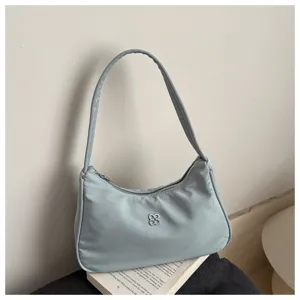 Close-up of a light blue minimalist nylon hobo shoulder bag with a silver logo.