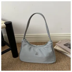 Detailed shot of a stylish light gray nylon armpit bag in a minimalist setting