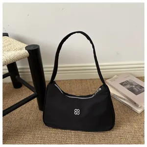 Detail view of the black minimalist shoulder bag showing the silver flower logo