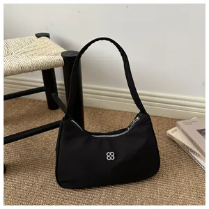 Minimalist black nylon underarm shoulder bag in a stylish lifestyle setting