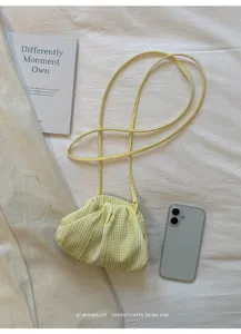 Detail of a yellow gingham pleated mini crossbody bag with a thin cord strap
