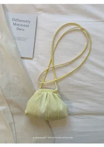 Detailed view of a yellow checkered pleated cloud bag in a minimalist retro setting