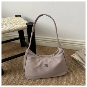 Close-up detail of elegant minimalist mauve nylon shoulder bag with silver floral logo