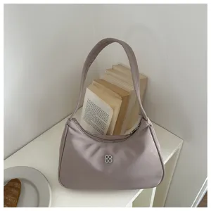 Detail of minimalist mauve underarm shoulder bag with silver clover logo decoration