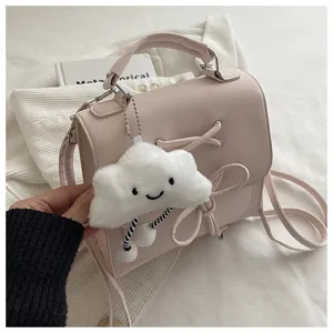 Detail einer rosa mattierten Handtasche mit einem süßen weißen Plüschwolken-Schlüsselanhänger