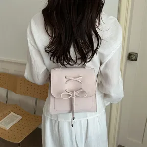 Modell trägt einen rosa mattierten Rucksack mit stilvollem, dekorativem Schleifendesign.